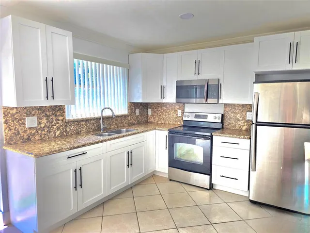a kitchen with granite countertop white cabinets and stainless steel appliances