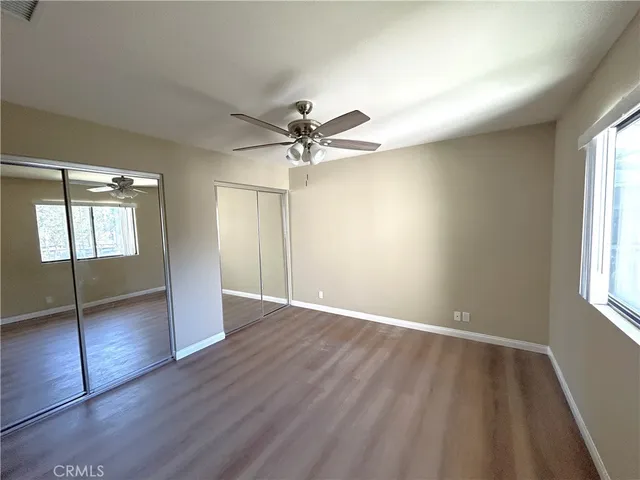 an empty room with wooden floor fan and windows