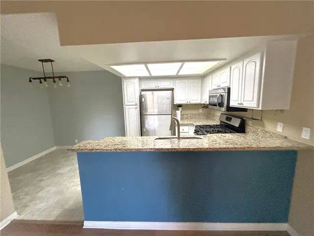 a kitchen with stainless steel appliances granite countertop a sink a stove cabinets counter space and a window