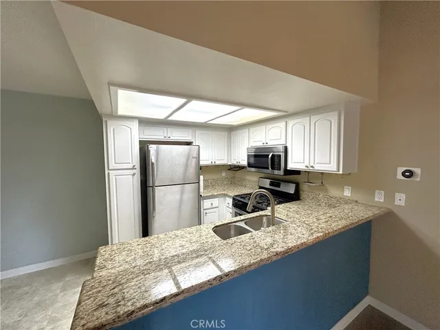 a kitchen with stainless steel appliances granite countertop a sink refrigerator and microwave