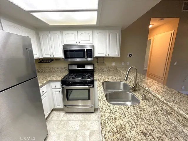 a kitchen with stainless steel appliances granite countertop a sink stove microwave and refrigerator