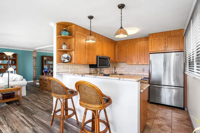 a kitchen with stainless steel appliances granite countertop a refrigerator a stove a sink dishwasher a dining table and chairs with wooden floor
