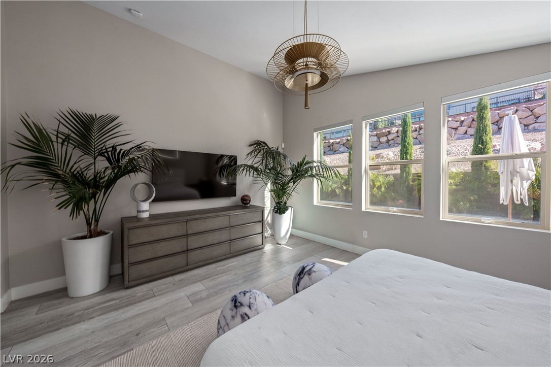 9719 Starlight Ridge Avenue Las Vegas, NV 89148 - Photo 12 of 25 A tranquil primary bedroom with light wood flooring and bright windows overlooking a private outdoor area.