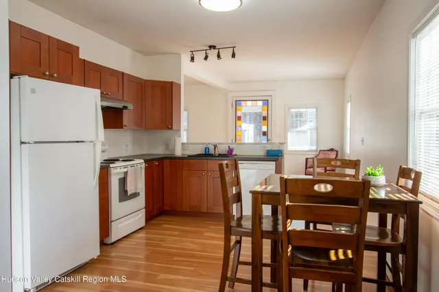 a kitchen with stainless steel appliances granite countertop a stove a refrigerator a dining table and chairs