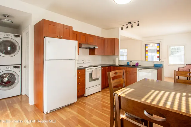 a kitchen with a refrigerator a stove a sink dishwasher and white cabinets with wooden floor