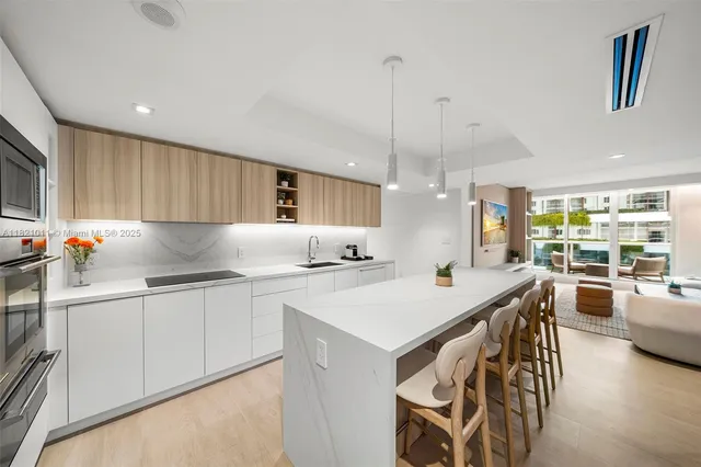 a kitchen with stainless steel appliances kitchen island a table chairs in it and wooden floors