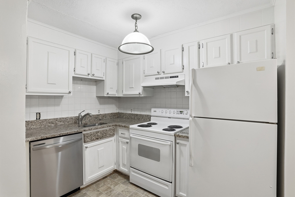 a kitchen with stainless steel appliances granite countertop a sink a refrigerator a stove and white cabinets