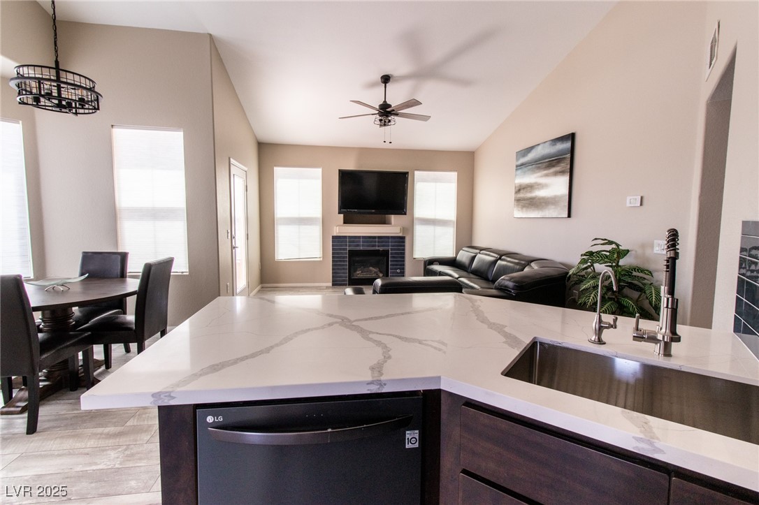 10550 West Alexander Road, Unit 2068 Las Vegas, NV 89129 - Photo 7 of 47 Kitchen with dishwasher, dark brown cabinets, a fireplace, light stone countertops, and decorative light fixtures