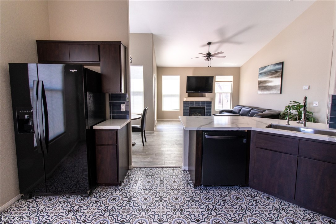 10550 West Alexander Road, Unit 2068 Las Vegas, NV 89129 - Photo 46 of 47 Kitchen featuring dark brown cabinetry, black appliances, open floor plan, a fireplace, and vaulted ceiling