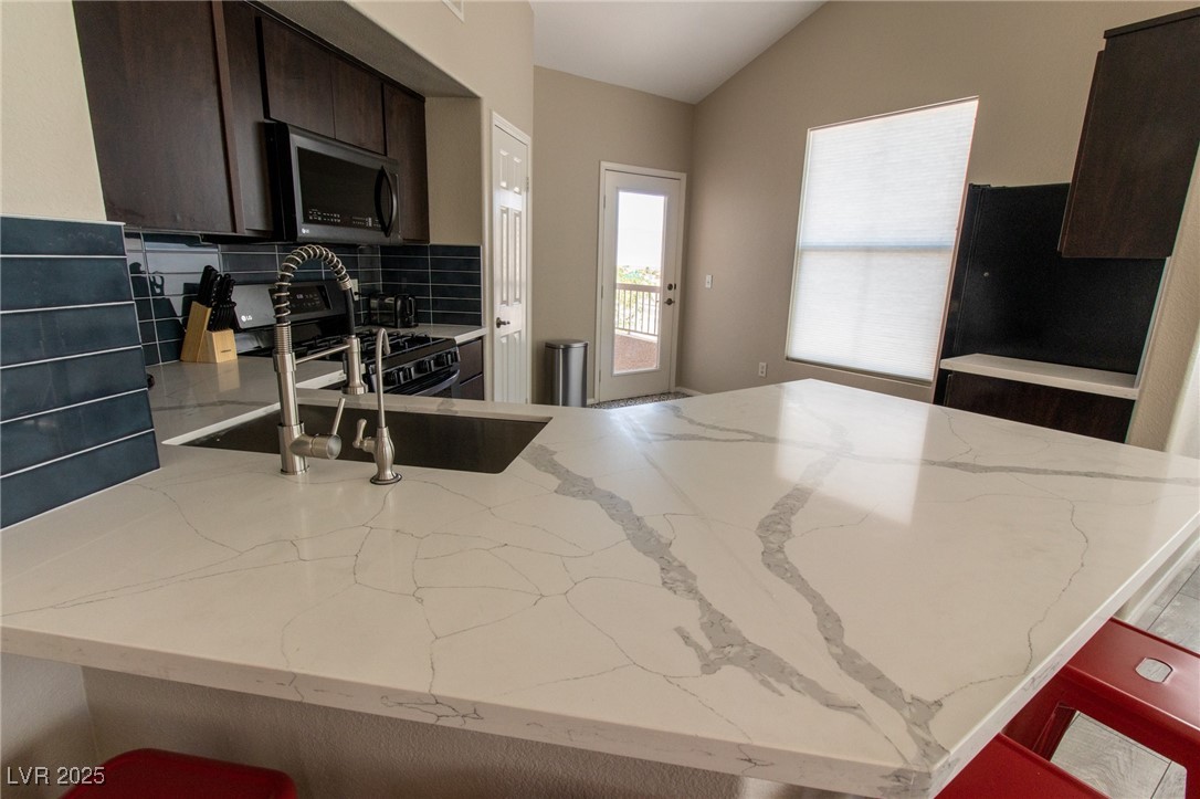 10550 West Alexander Road, Unit 2068 Las Vegas, NV 89129 - Photo 8 of 47 Kitchen featuring a breakfast bar, gas stove, light stone counters, tasteful backsplash, and a peninsula