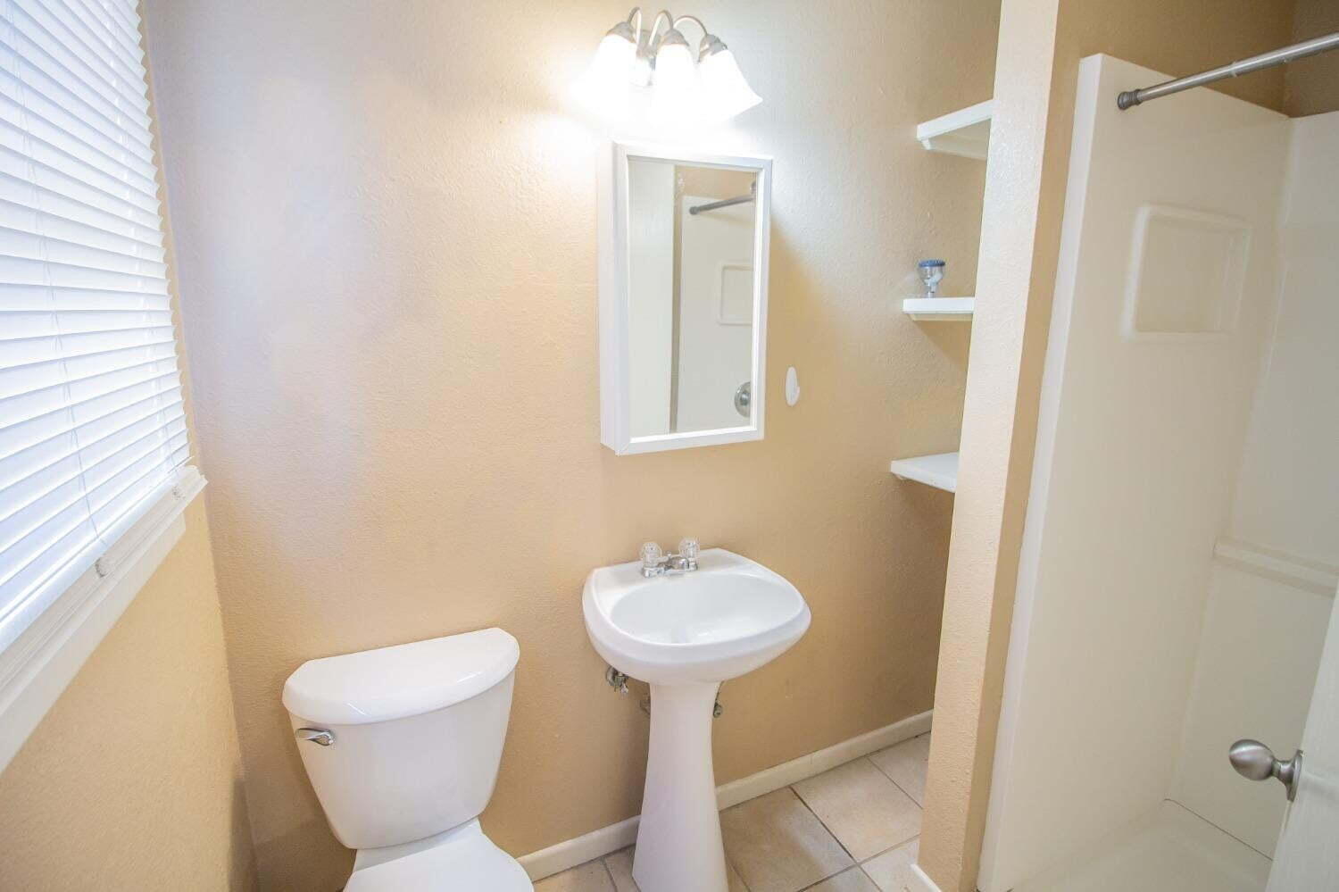 3813 35th Street Lubbock, TX 79413 - Photo 11 of 18 a bathroom with a sink toilet and a mirror