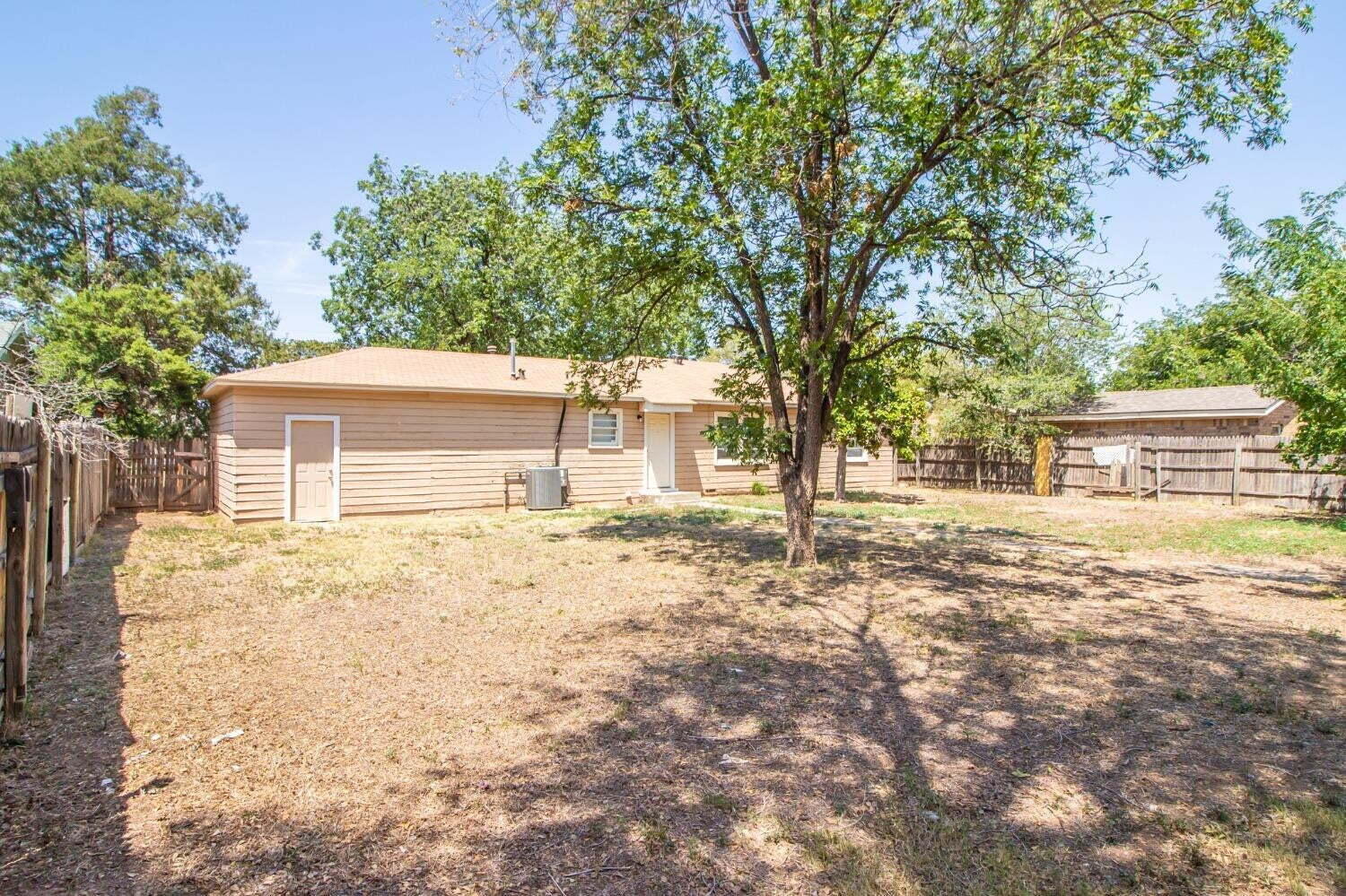 3813 35th Street Lubbock, TX 79413 - Photo 18 of 18 a backyard of a house with large trees and a barn