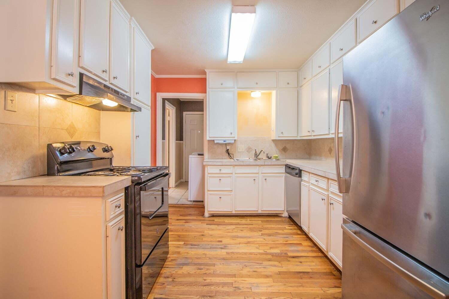 3813 35th Street Lubbock, TX 79413 - Photo 7 of 18 a kitchen with stainless steel appliances a refrigerator a sink and white cabinets
