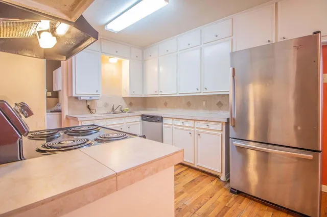 a kitchen with a refrigerator a stove a sink and white cabinets