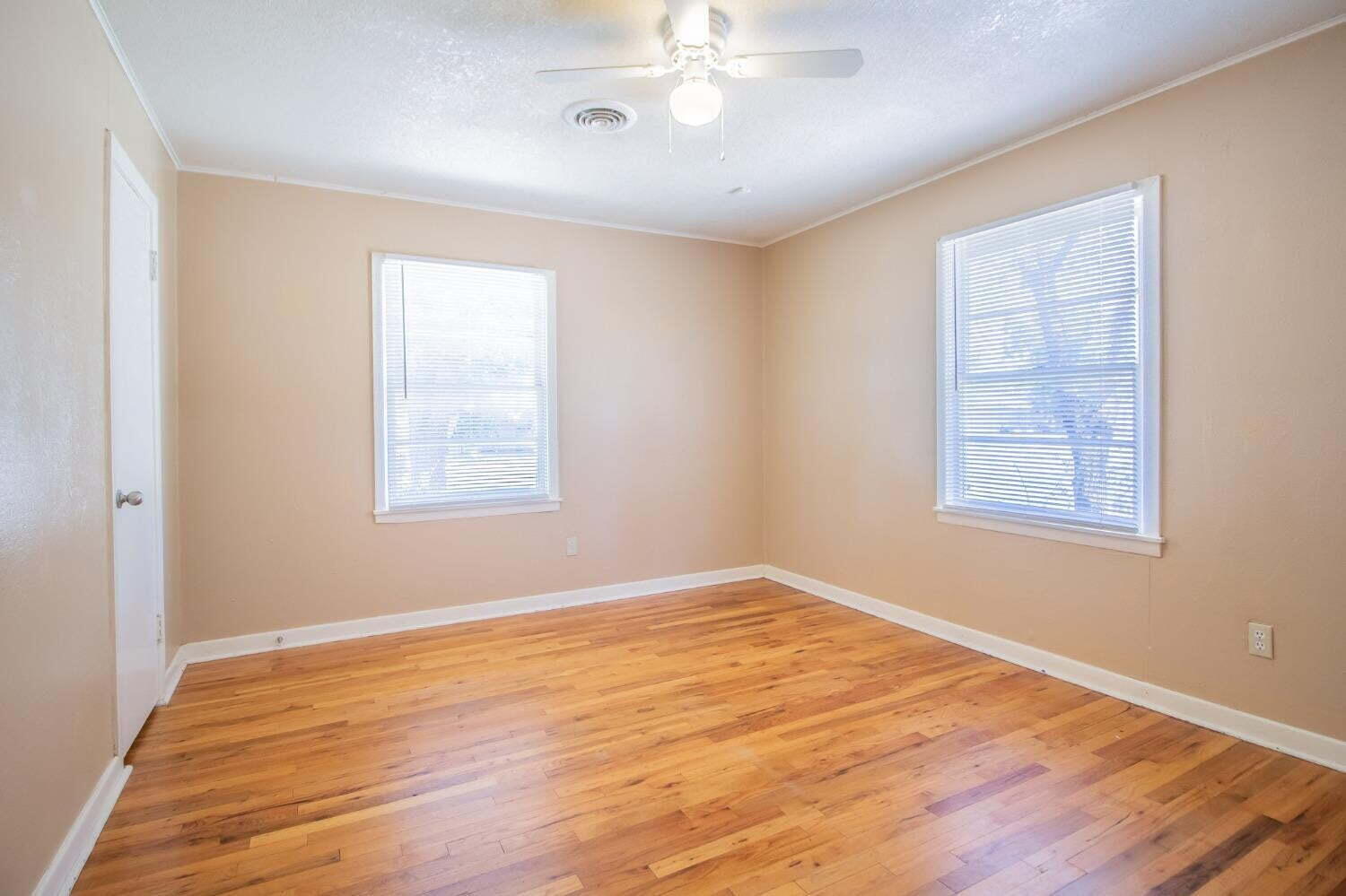 3813 35th Street Lubbock, TX 79413 - Photo 10 of 18 a view of an empty room with wooden floor and a window