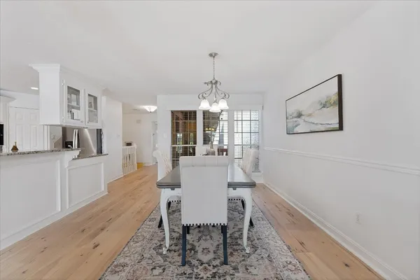 a large white dining hall with stainless steel appliances granite countertop a dining table chairs and couches