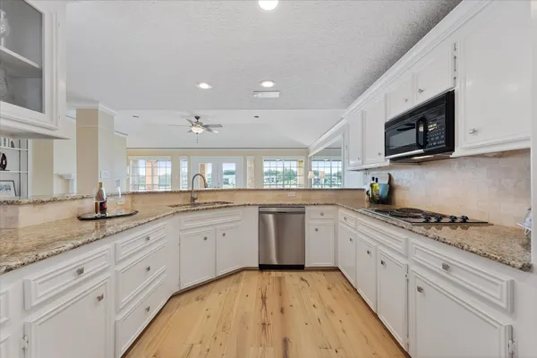 a kitchen with granite countertop sink stainless steel appliances and white cabinets