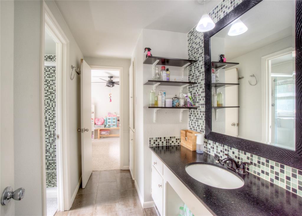 12231 Veronica Road Farmers Branch, TX 75234 - Photo 19 of 26 Bathroom featuring a black countertop, oval undermount sink, mosaic tile backsplash, and a large framed mirror