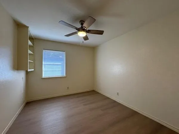 an empty room with a window and a fan