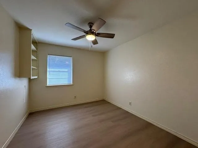an empty room with a window and a fan