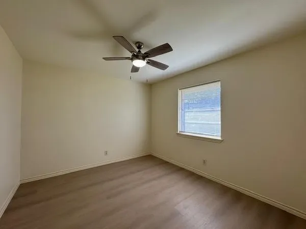 an empty room with a window and a fan