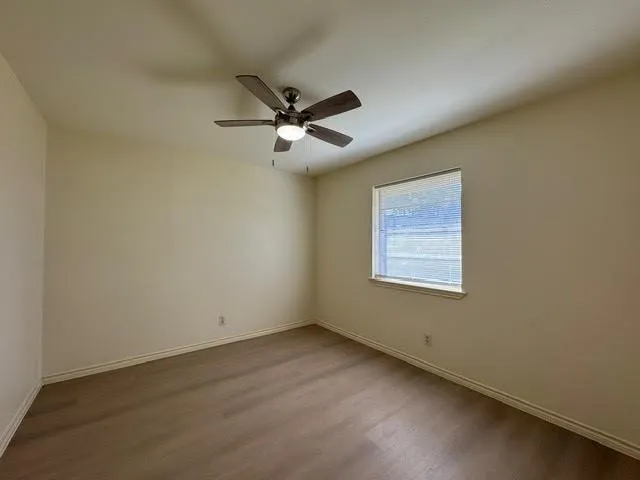 an empty room with a window and a fan