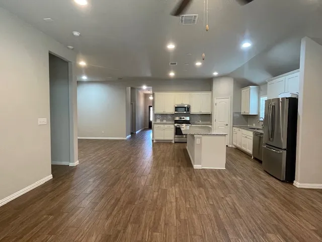 a kitchen with stainless steel appliances a refrigerator and wooden floor