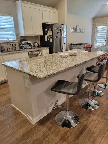 a kitchen with kitchen island granite countertop a sink and cabinets