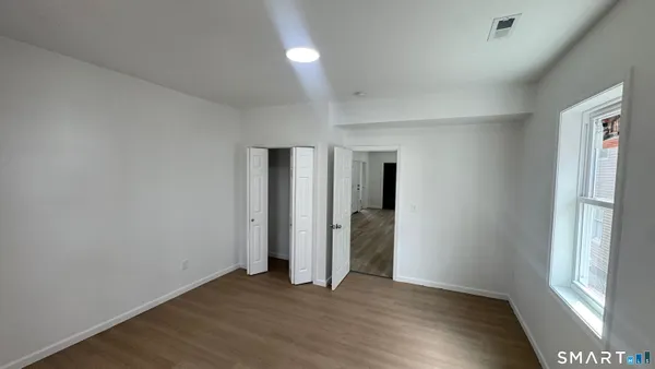 an empty room with wooden floor and windows