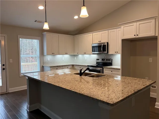a kitchen with kitchen island a counter space a sink a stove a refrigerator and cabinets