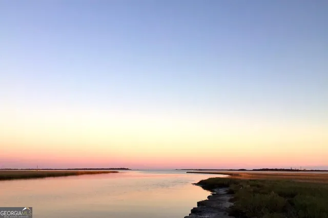 a view of a house with a yard and table and chairs under an umbrella