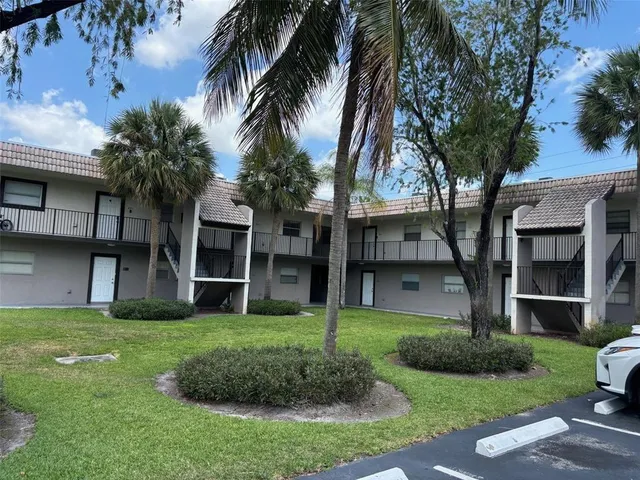 a front view of a house with a yard and palm trees
