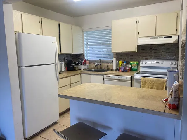 a kitchen with stainless steel appliances granite countertop a refrigerator a stove a sink and white cabinets