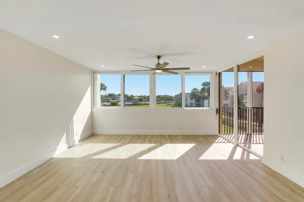 a view of empty room with wooden floor and ceiling fan