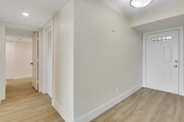 a view of an empty room with wooden floor and a large window