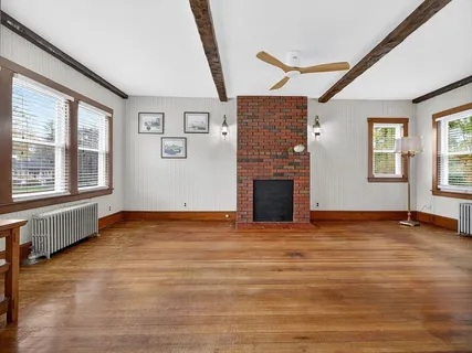 a view of an empty room with window and wooden floor