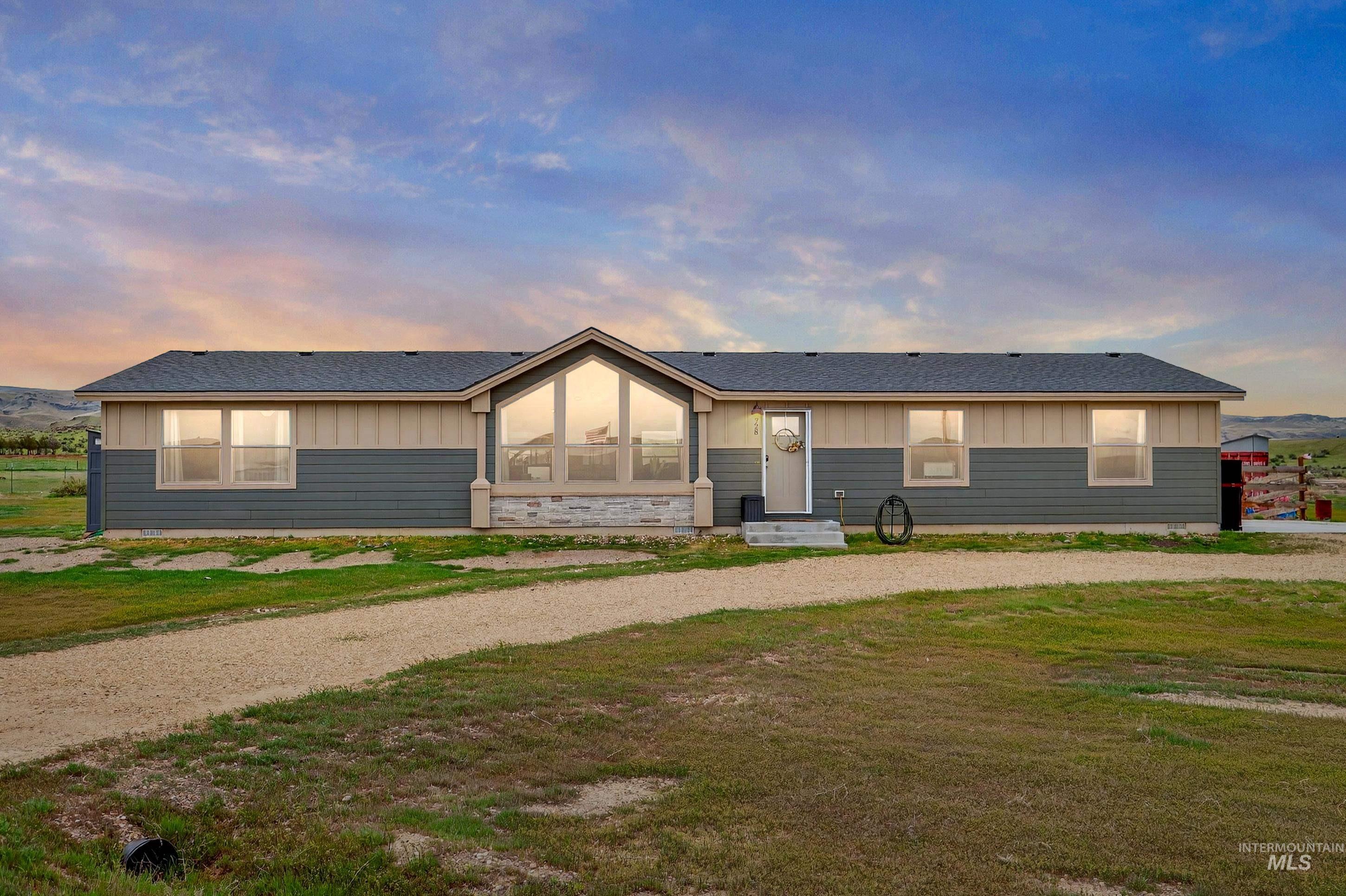 View of front of home featuring board and batten siding, roof with shingles, curved driveway, and a front yard