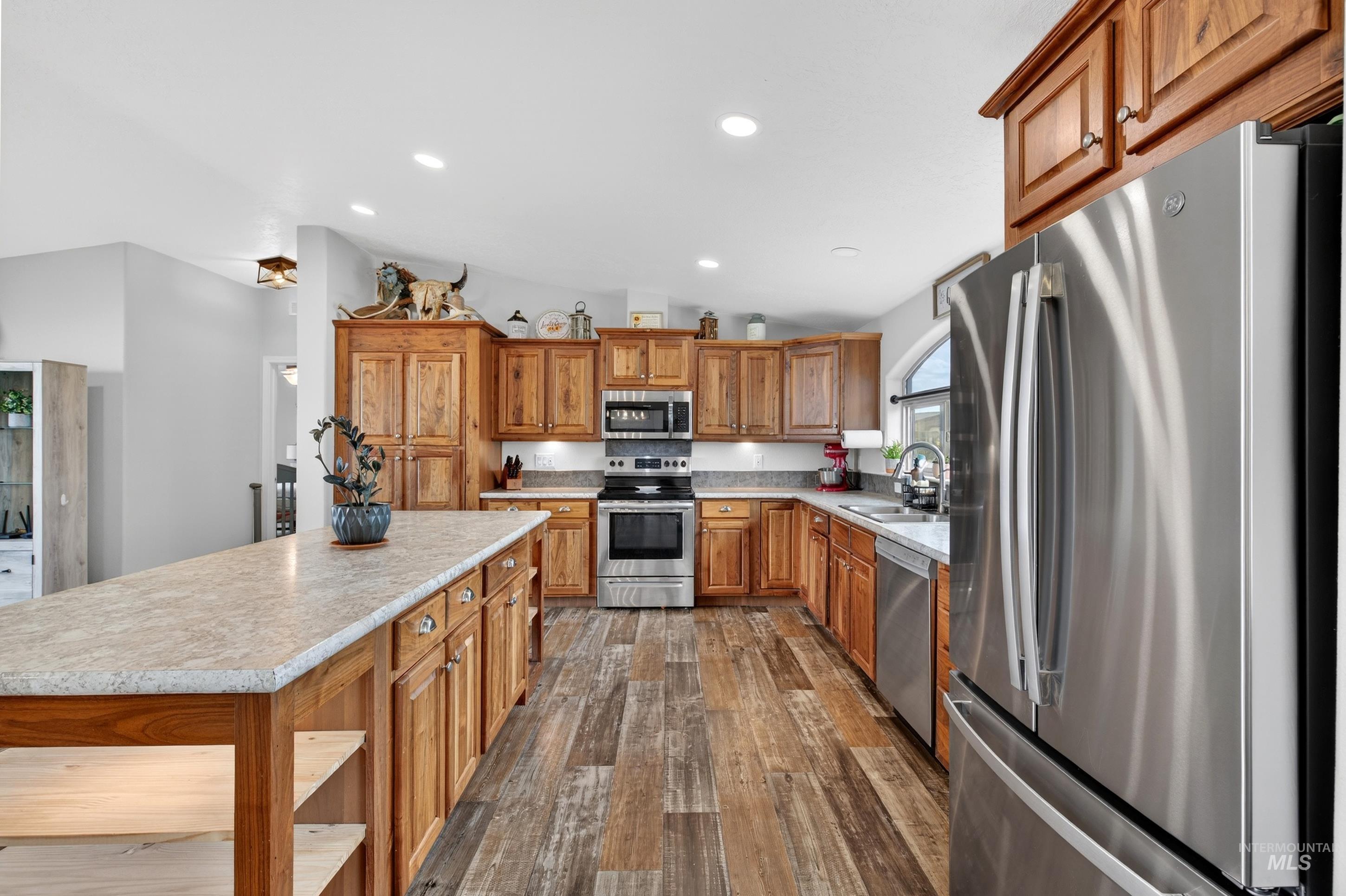 728 Chase Lane Melba, ID 83641 - Photo 15 of 48 Kitchen featuring stainless steel appliances, vaulted ceiling, light countertops, dark wood-type flooring, and wood finish cabinets