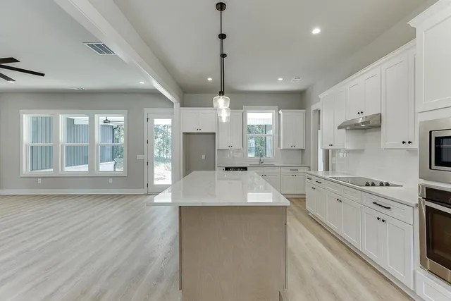 a large kitchen with granite countertop a large counter top appliances and cabinets