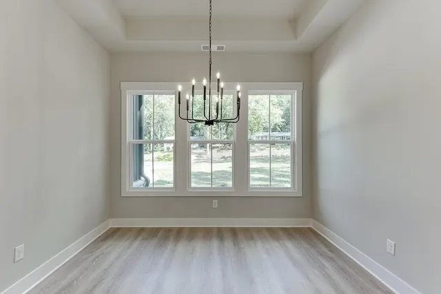 a view of an empty room with chandelier and window