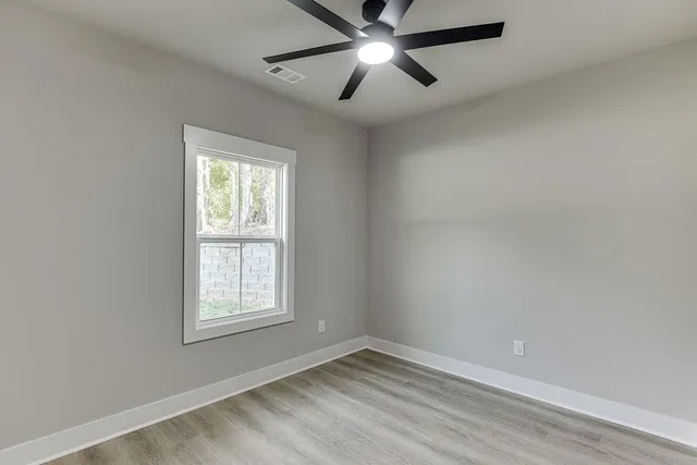 an empty room with a window and a fan