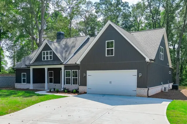 a front view of a house with a garden and trees