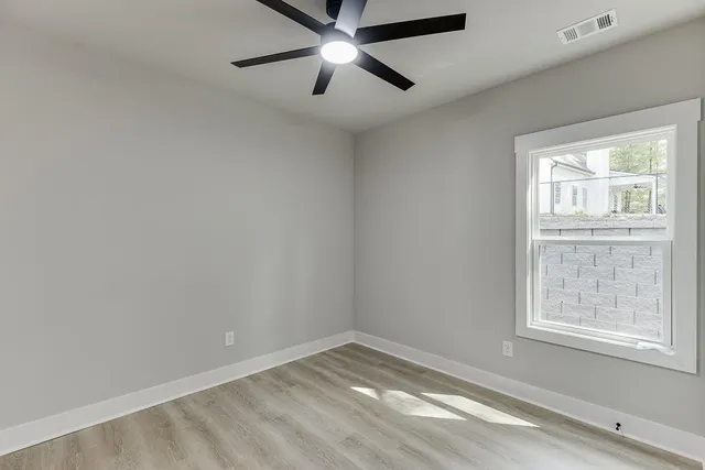 an empty room with a window and a ceiling fan