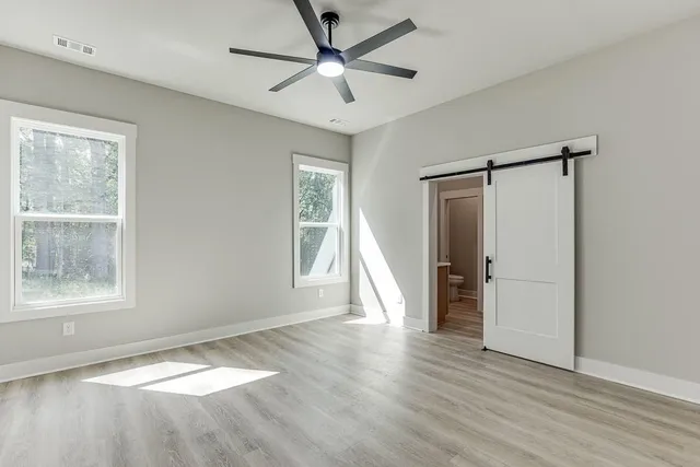 a view of an empty room with a window and wooden floor