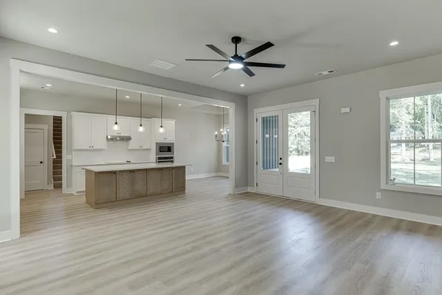 a large kitchen with kitchen island a island wooden floor stainless steel appliances and a window