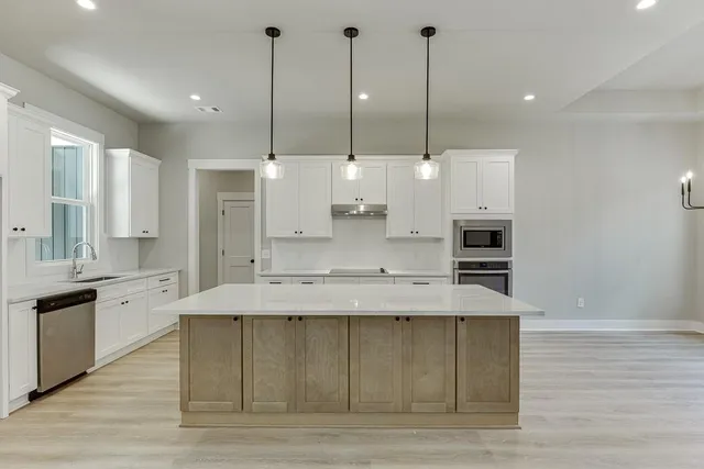 a large kitchen with kitchen island a stove a sink a counter space and wooden floor