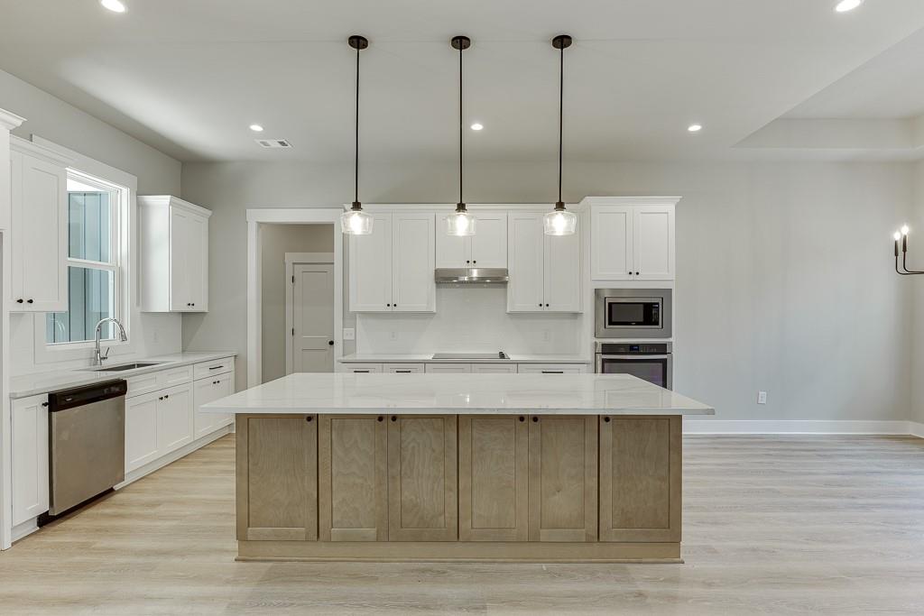 115 Rains Road Jefferson, GA 30549 - Photo 10 of 41 a large kitchen with kitchen island a stove a sink a counter space and wooden floor