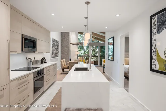 a view of a kitchen with kitchen island granite countertop a large counter top stainless steel appliances a sink a window and a window
