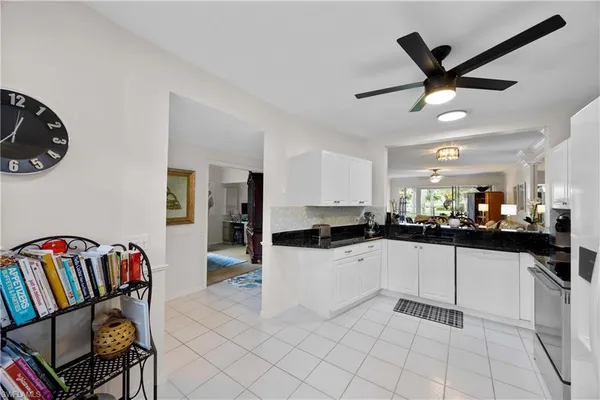 a kitchen with granite countertop a white refrigerator a sink a stove and white cabinets