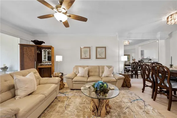 a living room with furniture kitchen view and a chandelier